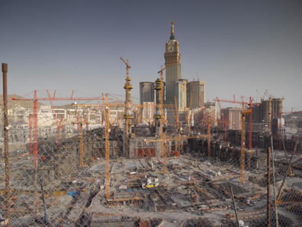 Blick auf eine Baustelle in Mekka mit zahlreichen Kränen und der Makkah Royal Clock Tower im Hintergrund.