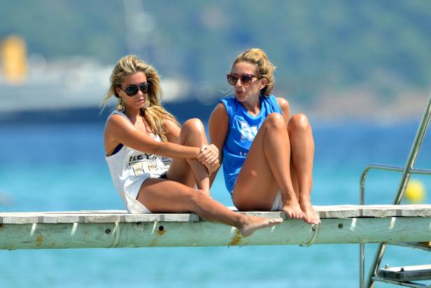 Zwei Frauen sitzen am Strand auf einem Holzsteg.