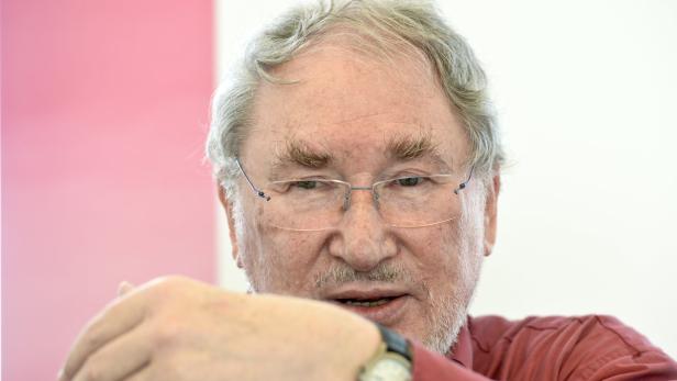 Ein Mann mit Brille und grauem Haar schaut in die Kamera.