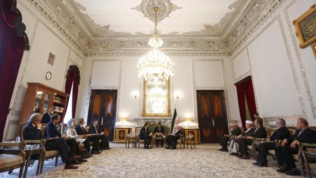 Eine Gruppe von Menschen sitzt in einem opulenten Raum für ein Treffen zusammen.