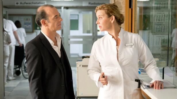 Ein Mann im Anzug spricht mit einer Ärztin in einem Krankenhaus.