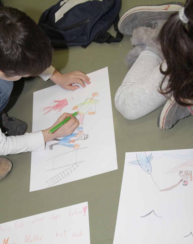 Ein Kind zeichnet mit einem grünen Stift ein Bild von mehreren Personen.