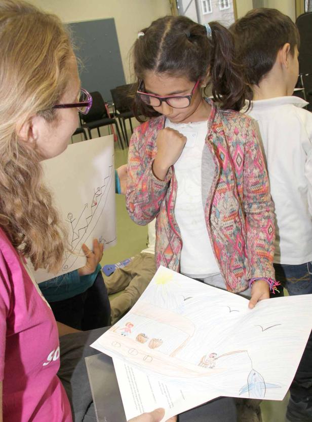 Ein Mädchen präsentiert stolz ihre Zeichnung von einem Boot mit Hai.