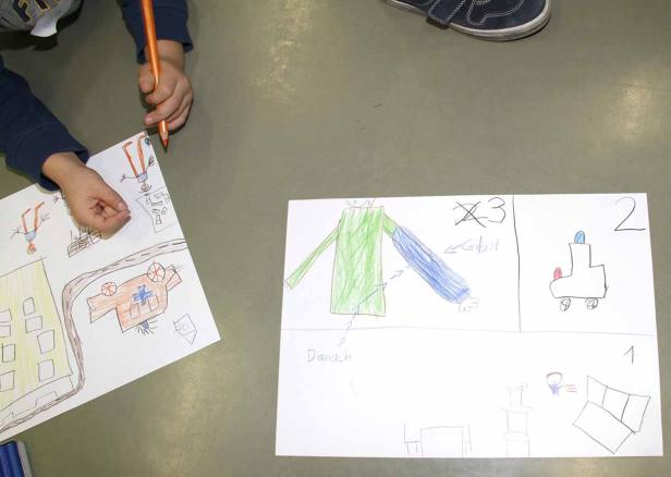 Ein Kind zeichnet mit Buntstiften Bilder auf Papier.