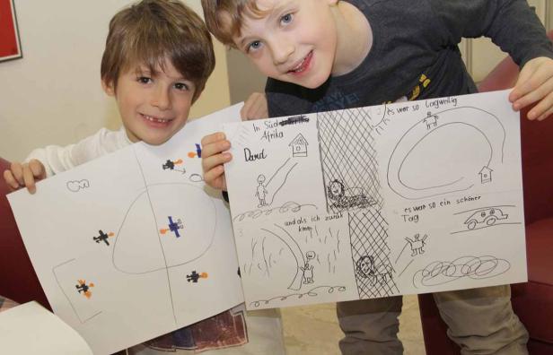 Zwei Jungen präsentieren eine selbstgezeichnete Bildergeschichte über eine Reise nach Südafrika.