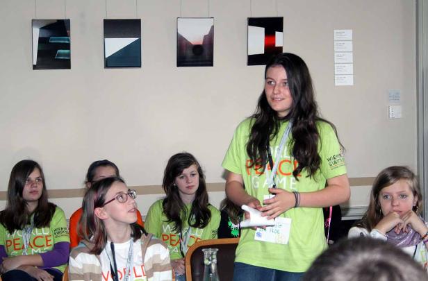 Eine junge Frau präsentiert vor einer Gruppe Jugendlicher ein Projekt zum Thema Frieden.