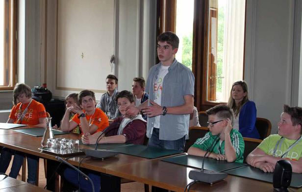 Ein junger Mann hält vor einer Gruppe von Jugendlichen einen Vortrag.