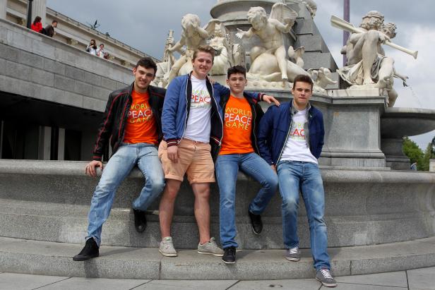 Vier junge Männer posieren vor dem Denkmalbrunnen am Schwarzenbergplatz in Wien.