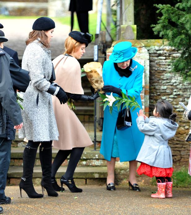 Königin Elisabeth II. nimmt Blumen von einem kleinen Mädchen entgegen.