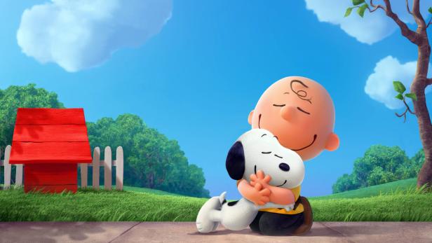 Charlie Brown umarmt Snoopy vor seinem roten Hundehaus.