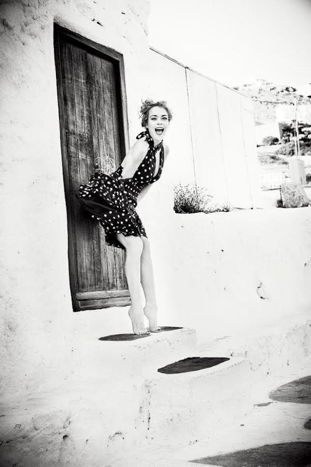 Ellen von Unwerth/No Tofu Magazine Eine Frau im gepunkteten Kleid steht barfuß auf einer Treppe und lacht.