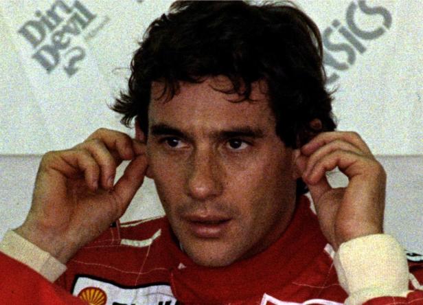 Ayrton Senna, ein Rennfahrer, berührt seine Ohren.