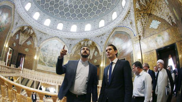 Zwei Männer besichtigen einen reich verzierten Kuppelbau mit Wandmalereien.