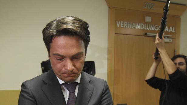 Ein Mann im Anzug mit Tränen in den Augen steht vor einem Verhandlungsraum.