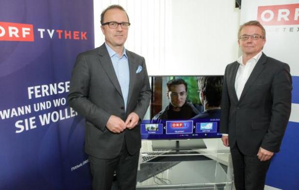Zwei Männer in Anzügen stehen vor einem Bildschirm mit dem ORF TVthek-Logo.