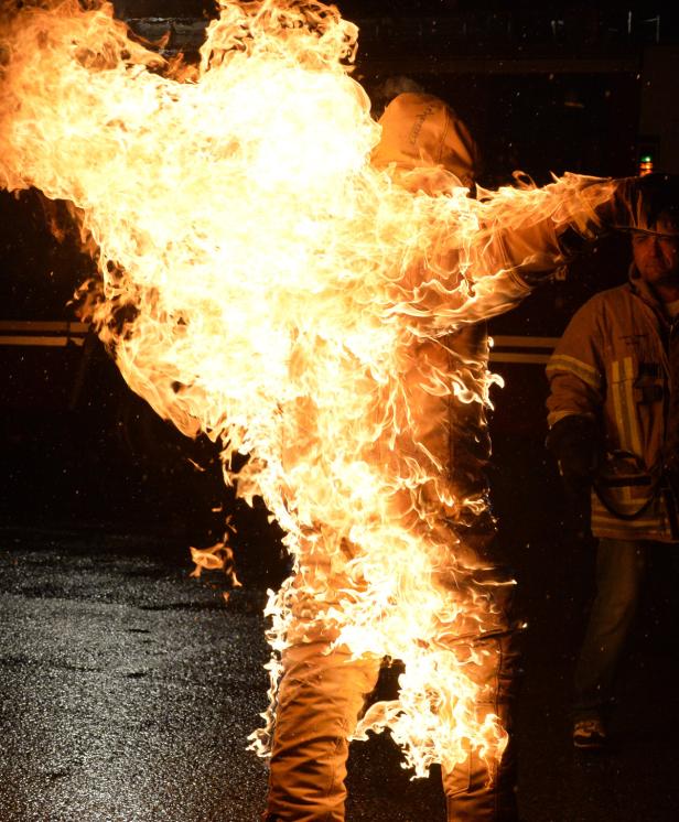 Eine Person in Schutzkleidung steht in Flammen.