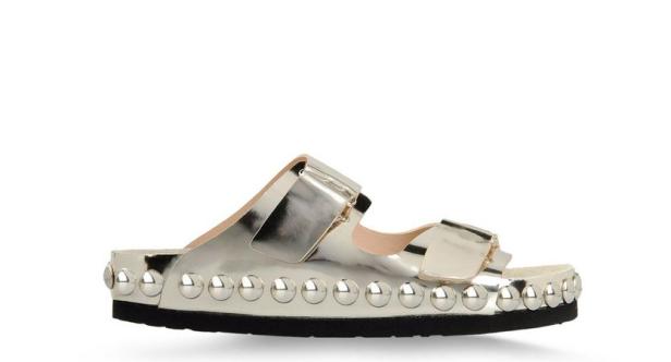 Silberfarbene Pantolette mit Nieten auf einer schwarzen Sohle.