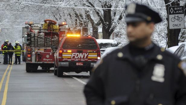 Ein Feuerwehreinsatz der FDNY auf einer verschneiten Straße, mit einem Polizisten im Vordergrund.
