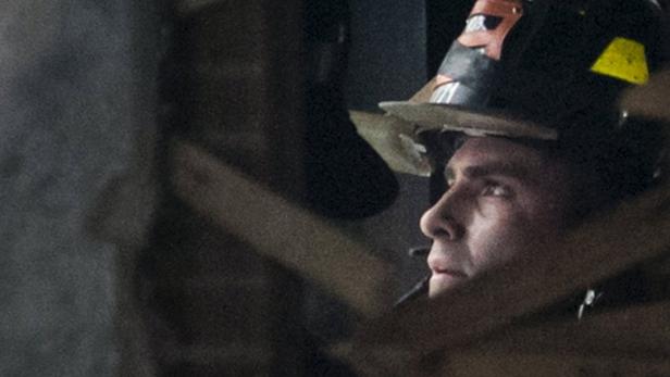 Ein Feuerwehrmann mit Helm blickt aufmerksam zur Seite.