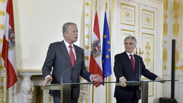 Zwei Männer stehen an Rednerpulten vor österreichischen und EU-Flaggen.