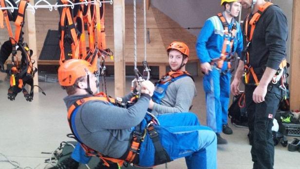 Mehrere Personen tragen Sicherheitsgurte und Helme bei einer Übung.