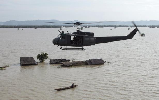 A military helicopter flies over a flooded village