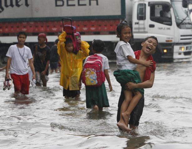 School children wade through floodwaters in Malabo