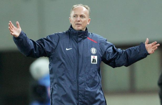 Ein Mann in einer blauen Jacke gestikuliert mit beiden Händen.