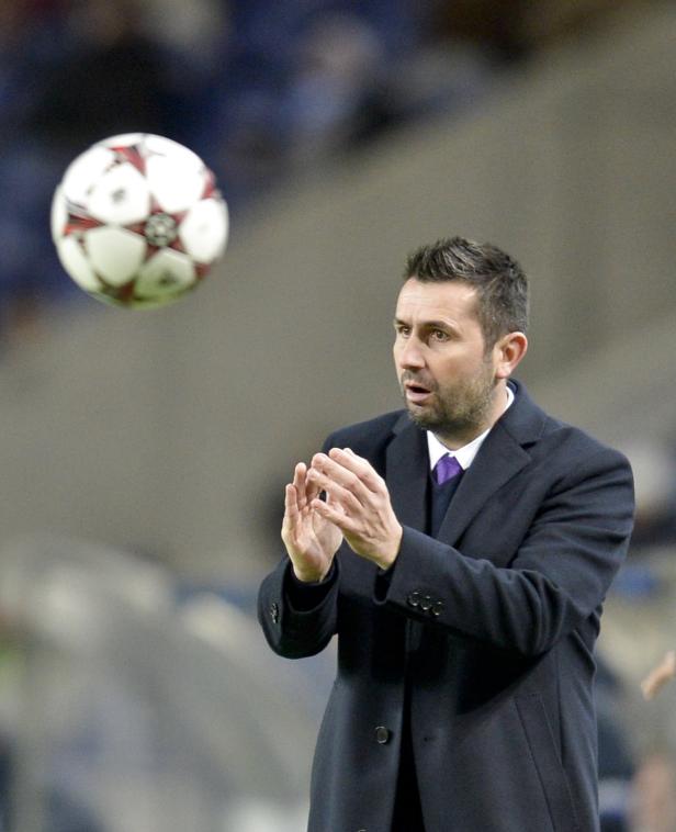 Ein Mann im Mantel klatscht, während ein Fußball in der Luft ist.