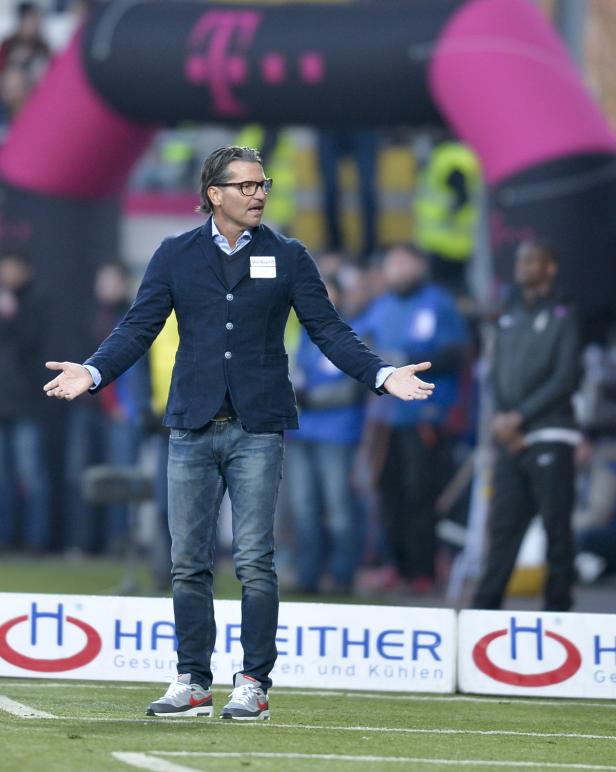 Ein Trainer mit Brille gestikuliert am Spielfeldrand.