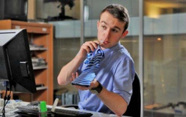 Ein Mann im Büro bindet seine blau-gestreifte Krawatte.