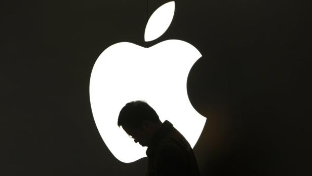 Die Silhouette eines Mannes vor einem hell erleuchteten Apple-Logo.