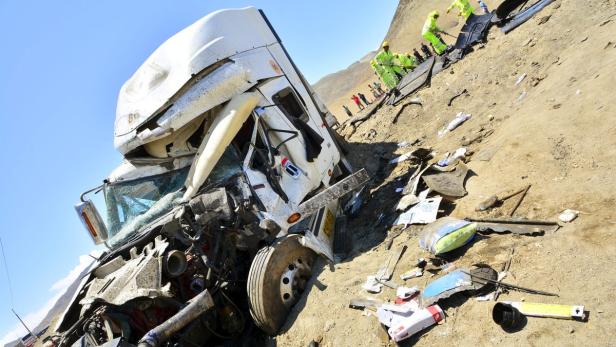 Ein verunglückter Lastwagen liegt auf einer sandigen Böschung, umgeben von Trümmern.