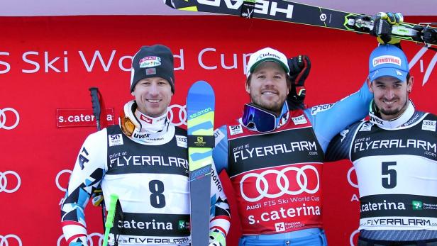 Drei Skirennläufer stehen auf dem Podium eines Ski Weltcup Rennens.