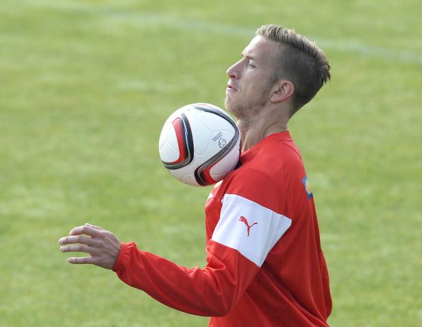 Ein Mann im roten Trikot balanciert einen Fußball auf seinem Hals.