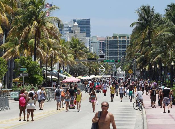 Eine belebte Straße in Miami Beach mit Palmen und vielen Menschen.