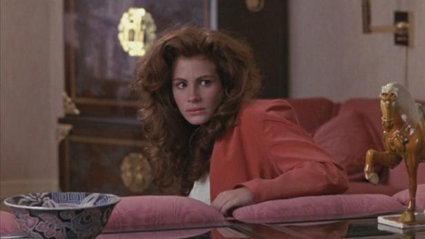Julia Roberts sitzt in einem roten Blazer auf einem Sofa.
