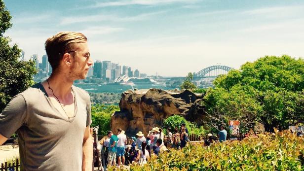 Ein Mann blickt auf die Skyline von Sydney mit dem Opernhaus und der Harbour Bridge im Hintergrund.