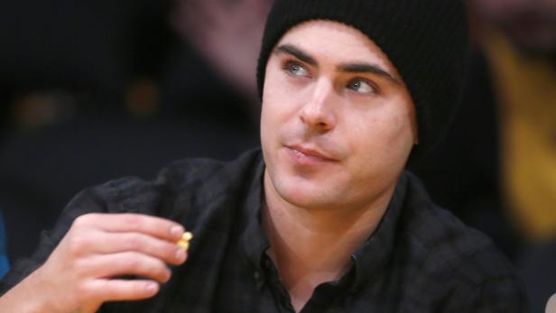 Zac Efron mit Mütze isst Popcorn.
