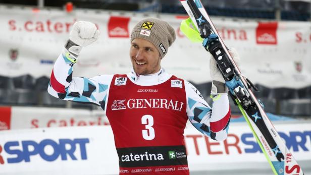 Ein Skirennläufer jubelt mit erhobener Faust und Skiern in der Hand.