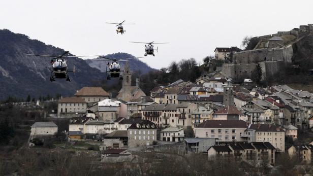 Drei Hubschrauber fliegen über eine Stadt mit einer Festung auf einem Hügel.