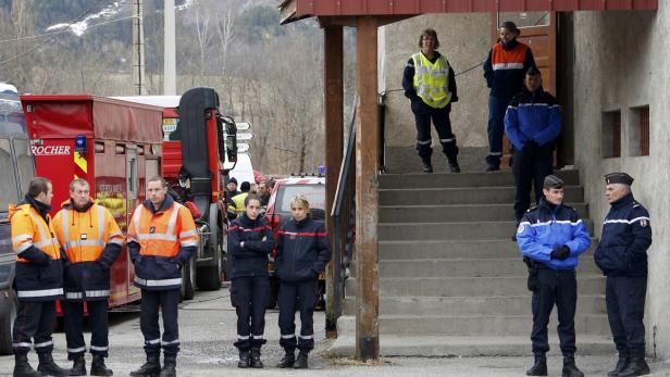 Eine Gruppe von Feuerwehrleuten und Polizisten steht vor einem Gebäude.