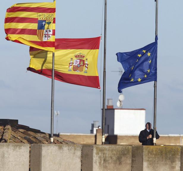 Die Flaggen von Katalonien, Spanien und der Europäischen Union wehen auf einem Dach.