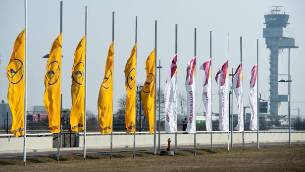 Gelbe Lufthansa-Flaggen und Germanwings-Flaggen wehen vor einem Flughafen-Kontrollturm.
