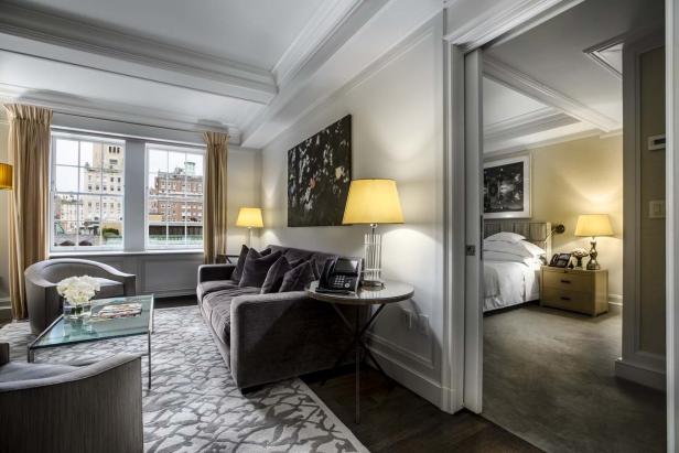 Ein Wohnzimmer mit einem Sofa, Sesseln und Blick durch das Fenster auf die Stadt.