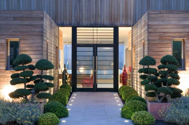 Ein moderner Hauseingang mit Holzwänden und einem gepflasterten Weg.