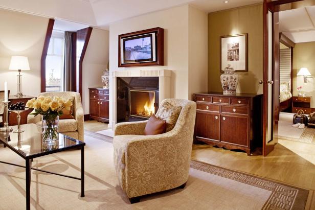 Ein Wohnzimmer mit Sesseln, Kamin und einem Fernseher darüber.