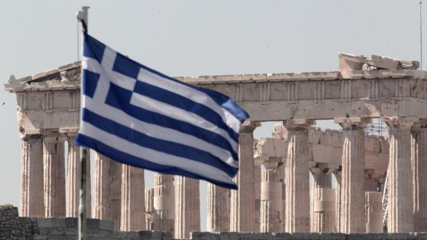 Die griechische Flagge weht vor dem Parthenon in Athen.