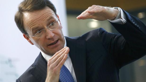 Ein Mann mit Brille und Anzug gestikuliert mit seinen Händen.