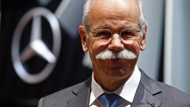 Dieter Zetsche, ehemaliger Vorstandsvorsitzender von Daimler, lächelt vor einem Mercedes-Benz Logo.